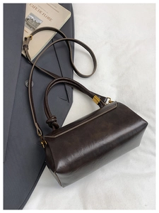 Detail of dark brown leather handbag with woven knot handle and vintage gold hardware