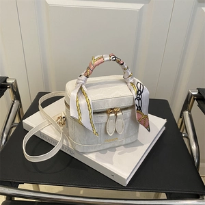 Detail of white marble pattern handbag with decorative silk scarf handle and gold text