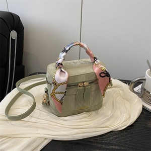 Detail of light green leather handbag with dual zippers and decorative floral scarf handle