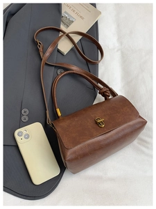 Detail of vintage brown PU leather square bag with gold twist lock and knotted handle