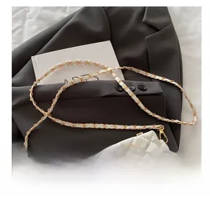 Close-up of white quilted crossbody bag with gold bow detail and metal chain strap