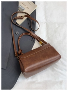 Detail of caramel brown leather handbag texture with retro gold hardware on grey suit