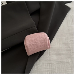 Close-up of a pink mini jewelry pouch with lychee leather texture on black fabric