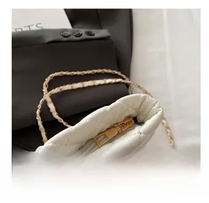 Detail of smooth metal zipper and gold chain strap on white quilted crossbody bag
