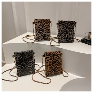 Four stylish leopard print chain crossbody bags displayed on minimalist white stands