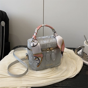 Detail of grey square handbag with silk scarf handle and golden fashion text