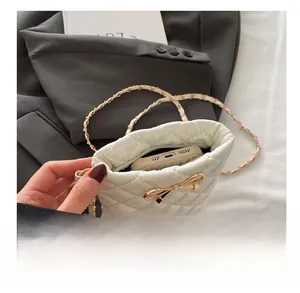 Close-up of white quilted mini bag interior capacity and gold bow chain details