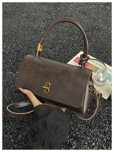 Detailed close-up of dark brown vintage leather handbag with antique gold metal hardware