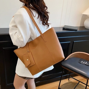 Caramel brown vintage leather tote bag with small pouch shown on a stylish model