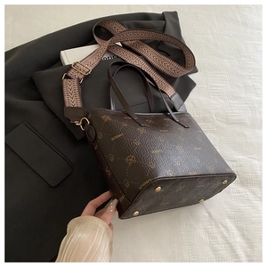 Detail of vintage tote bag with bear monogram, leather texture, and gold metal rivets