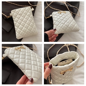 Macro detail of white quilted leather phone bag with a golden metal bow and chain strap
