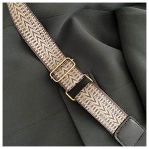Détail de la bandoulière bohème tissée réglable avec boucle dorée sur veste