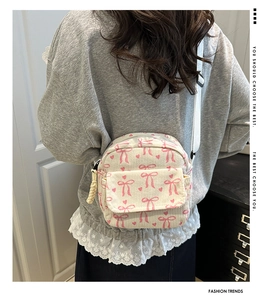 Détail d'un mini sac à dos en velours côtelé crème avec nœuds roses et motifs cœurs