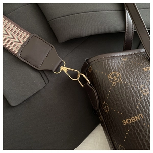 Détail du sac seau en cuir café avec imprimé doré et bandoulière tissée géométrique