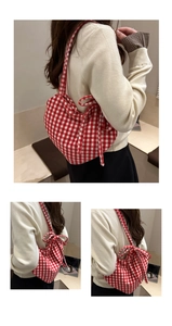 Detail of red and white gingham fabric underarm bag with decorative bow and checkered pattern