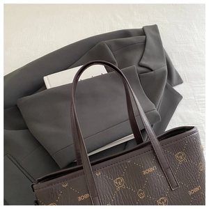Détail du sac seau en cuir marron foncé avec motifs gaufrés sur un tissu de costume gris