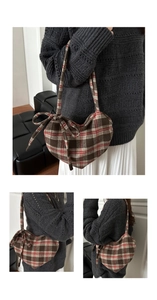Macro detail of a heart-shaped plaid shoulder bag featuring a stylish decorative bow tie