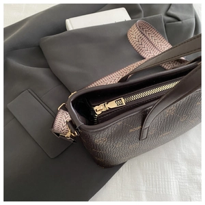 Gros plan détaillé d'un sac seau en cuir marron foncé avec motifs vintage et zip doré brillant
