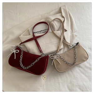 Détail de sacs à bandoulière bordeaux et abricot avec chaînes et nœuds en perles