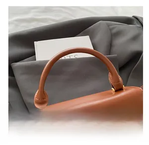Close-up of caramel leather handbag handle with gold hardware and refined stitching