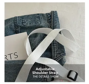 Détail de la bandoulière réglable sur le sac à dos en denim bleu avec tissu blanc