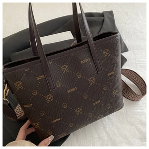 Détail du sac seau en cuir marron avec motif logo et bandoulière tissée colorée