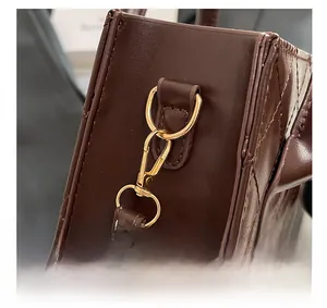 Détail de la quincaillerie en métal doré sur le sac en cuir marron matelassé