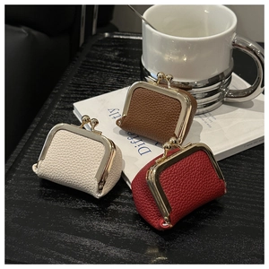 Detailed view of mini kiss-lock coin purses in creamy white, dark brown, and vibrant red
