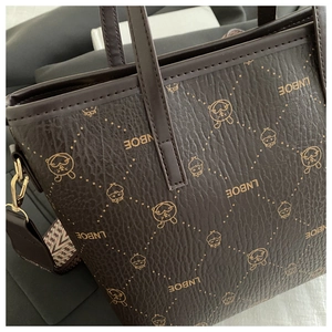Détail du sac seau en cuir marron avec motifs lapin et bandoulière en toile tissée
