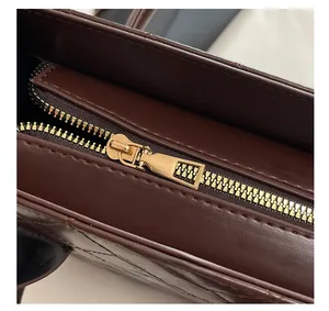 Détail macro du zip doré et du motif matelassé sur le sac à main en cuir marron
