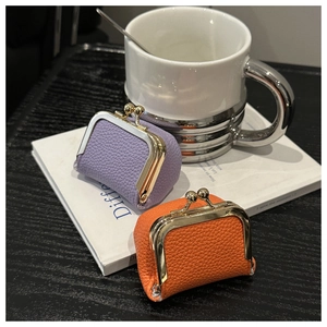 Close-up of purple and orange litchi grain leather mini pouches with gold metal clasps