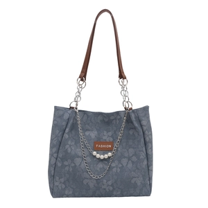 Bolso de hombro denim floral con correas marrones y detalle de cadena de perlas sobre blanco