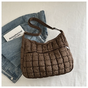Macro view of dark brown quilted bubble bag texture with metallic silver zipper detail