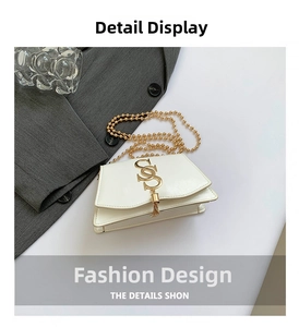 Detail of white leather shoulder bag with gold S-logo, tassel, and beaded chain strap