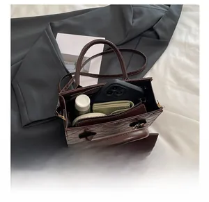 Intérieur de sac matelassé marron foncé montrant l'espace pour téléphone et maquillage