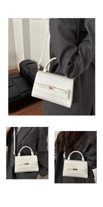 Detail of white leather handbag showing gold twist lock and fine stitching details