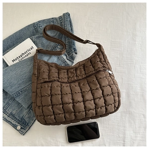 Detail showing the coffee brown quilted fabric texture and front zipper pocket of the bag