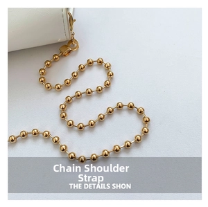Detail view of the elegant golden ball chain strap attached to a white leather crossbody bag