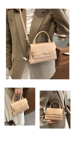 Detail of elegant beige leather handbag with gold metal clasp and adjustable shoulder strap