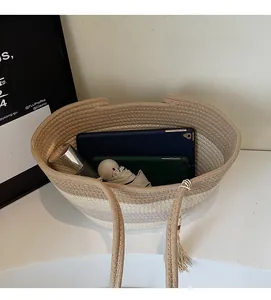Spacious interior of a woven straw tote bag holding an umbrella, devices and a spray