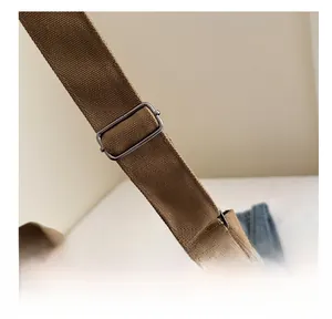 Detail of adjustable metal buckle on brown canvas strap of shoulder tote bag