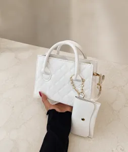 Detail of white quilted handbag featuring a mini pouch and golden chain link accessory