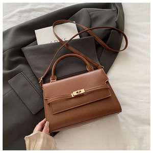 Detail of premium brown leather tote bag with gold twist-lock and structured top handle