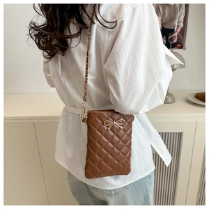 Détail du sac bandoulière matelassé marron avec nœud doré et chaîne en métal élégante