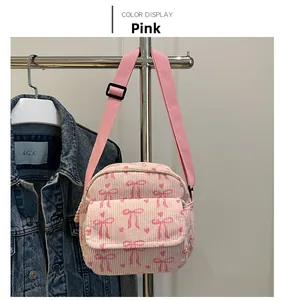 Détail du tissu en velours côtelé rose avec motifs de nœuds et cœurs et bandoulière réglable