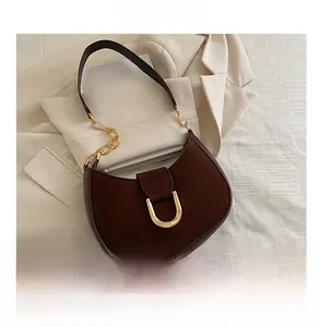 Dettaglio borsa hobo marrone scuro con fibbia a U dorata e texture scamosciata elegante