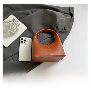 Detailed top view of a mini caramel leather handbag next to a smartphone