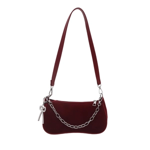Deep burgundy velvet shoulder bag with silver chain and crystal bow charm on white background