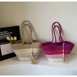 Detail of woven straw tote bags with gradient stripes and wooden bead tassels