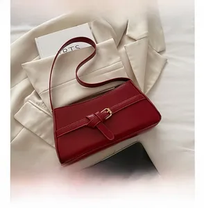 Detailed macro view of dark red matte leather texture with gold square buckle on shoulder bag